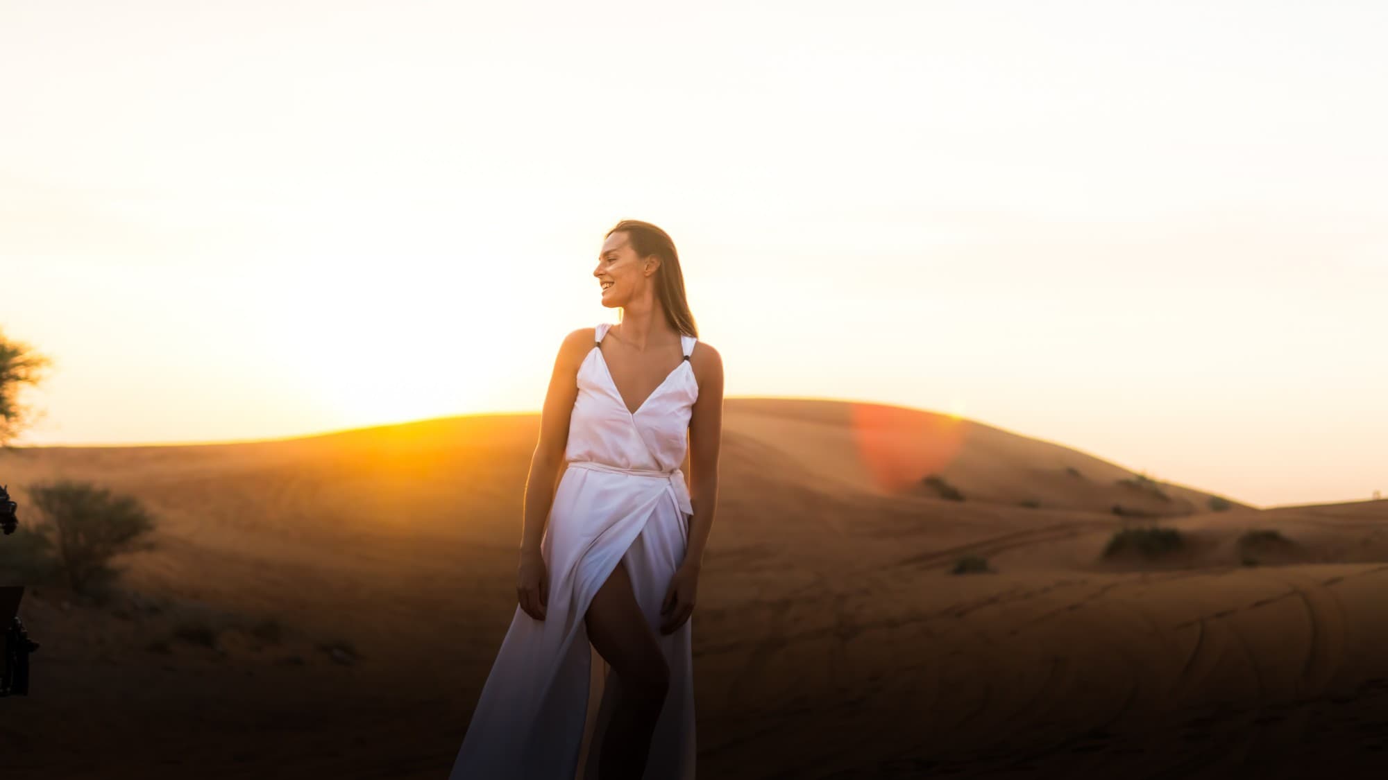 A woman in a white dress on the dunes at sunset