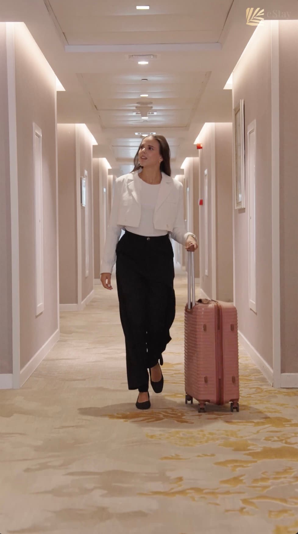 E& stay Hotel — A guest walking down the corridor with a pink suitcase